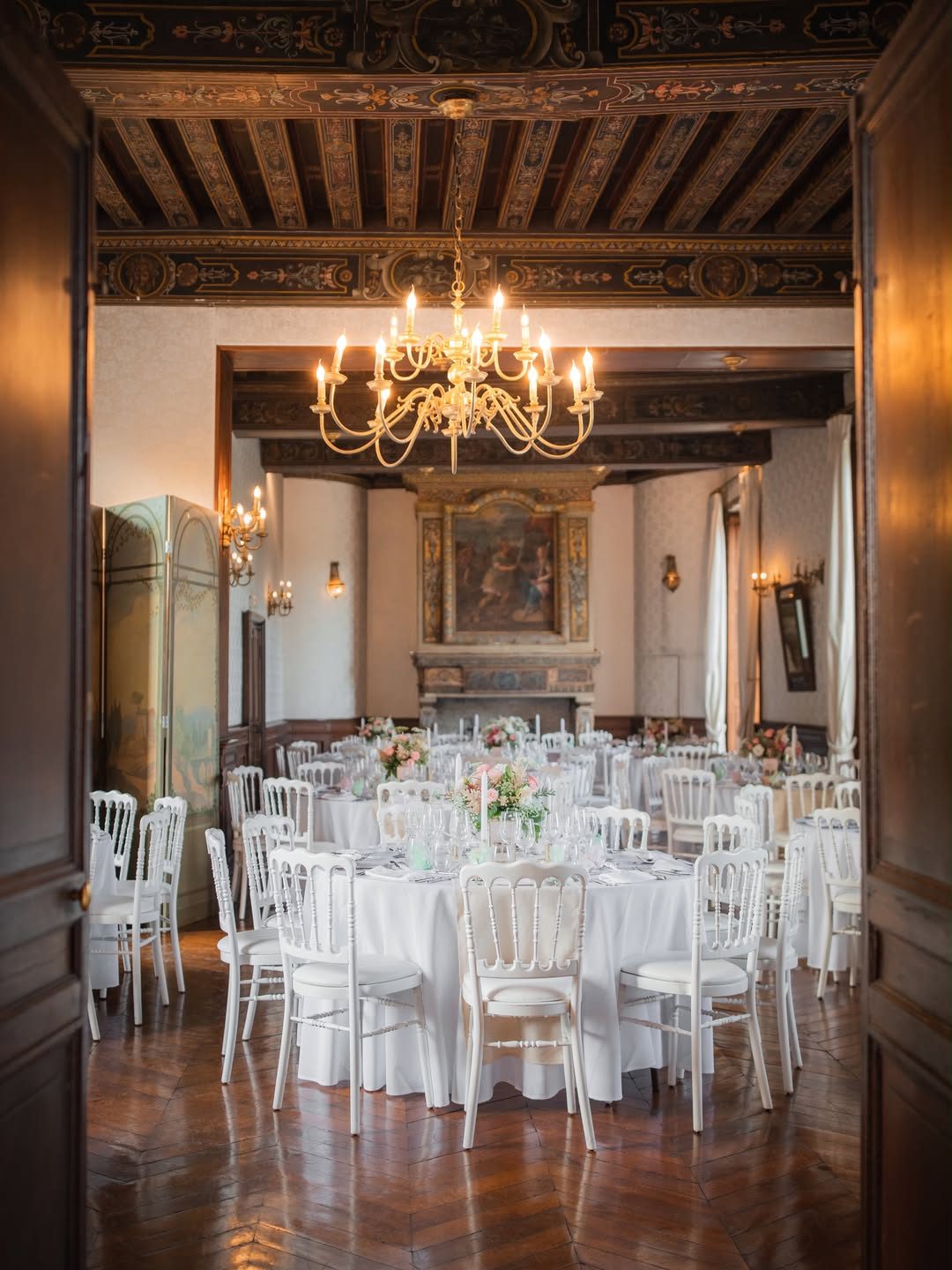 Un salon dressé pour un dîner, tables rondes sous le lustre