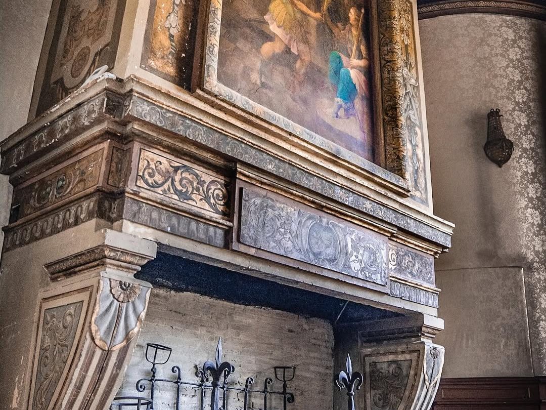 Une cheminée de pierre sculptée surmontée d'un dessus peint