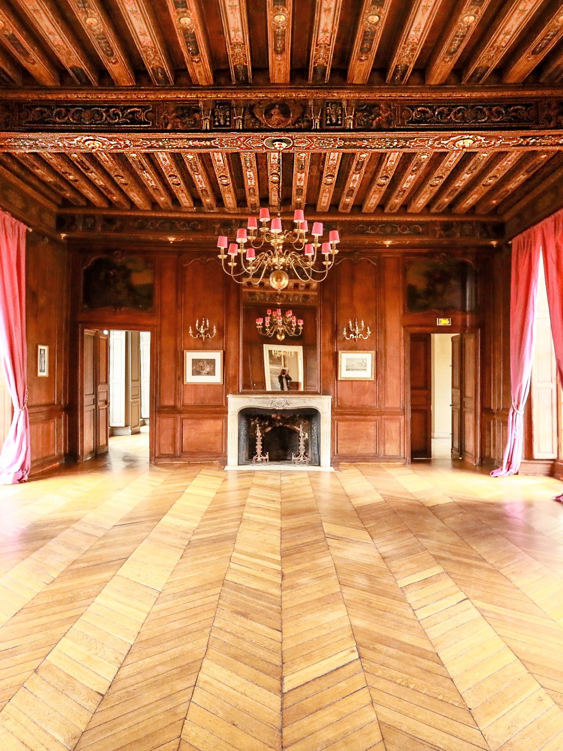 La salle de bal, parquet d'origine, lustre et rideaux rouges