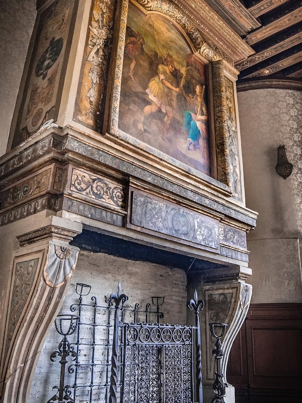 Une cheminée de pierre sculptée surmontée d'un dessus peint